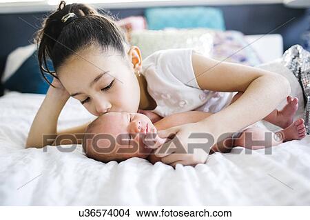 Picture - Girl (10-11) kissing brother with care (2-5 months). Fotosearch