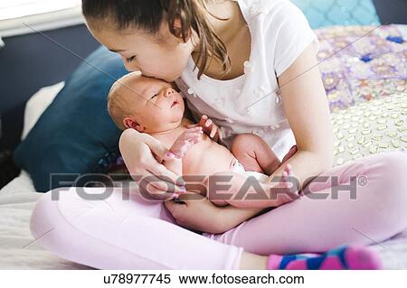 Stock Photography - Girl (10-11) kissing brother with care (2-5 months). Fotosearch