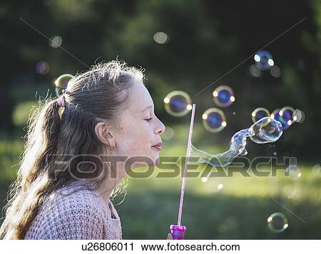 Stock Image - Girl (12-13) blowing bubbles. Fotosearch