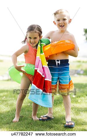 Girl (4-5) and boy (6-7) holding towel and inflatable rings View Large Photo Image Stock Photo - Girl (4-5) and boy (6-7) holding towel and inflatable rings. Fotosearch