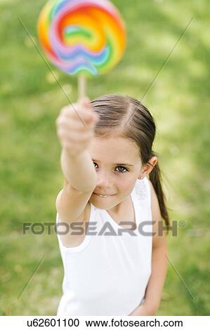 Stock Image - Girl (4-5) holding colorful lollipop. Fotosearch