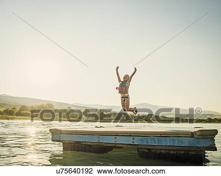 Girl (4-5) jumping into lake from pier View Large Photo Image Stock Image - Girl (4-5) jumping into lake from pier. Fotosearch