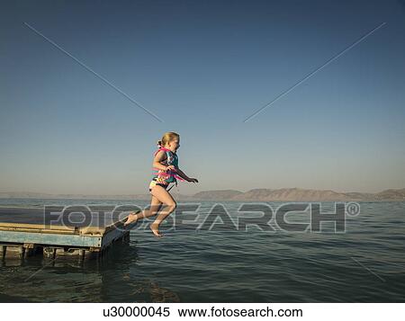 Stock Photography - Girl (4-5) jumping into lake from pier. Fotosearch
