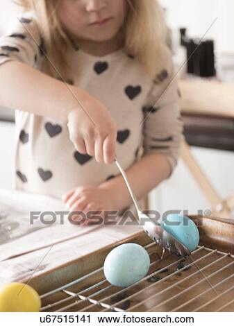 Stock Image - Girl (4-5) making colored Easter eggs. Fotosearch