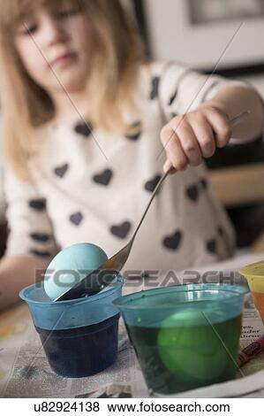 Stock Photo - Girl (4-5) making colored Easter eggs. Fotosearch