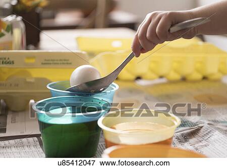 Stock Photo - Girl (4-5) making colored Easter eggs. Fotosearch