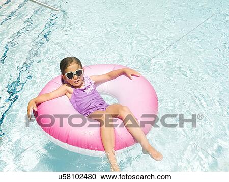 Stock Image - Girl (4-5) relaxing in inflatable ring. Fotosearch