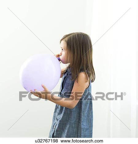 Girl (6-7) blowing balloon View Large Photo Image Stock Photo - Girl (6-7) blowing balloon. Fotosearch