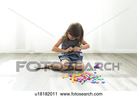 Stock Image - Girl (6-7) playing with plastic blocks. Fotosearch