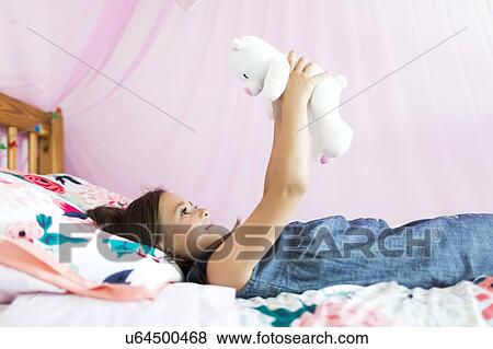 Girl (6-7) playing with teddy bear in bedroom View Large Photo Image Stock Photo - Girl (6-7) playing with teddy bear in bedroom. Fotosearch