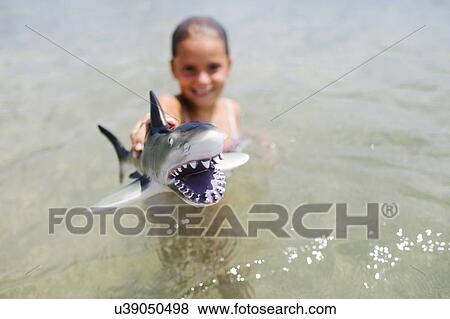 Girl (6-7) playing with toy shark in sea View Large Photo Image Stock Photo - Girl (6-7) playing with toy shark in sea. Fotosearch