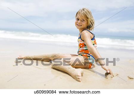 Picture - Girl (6-7) sitting on beach. Fotosearch