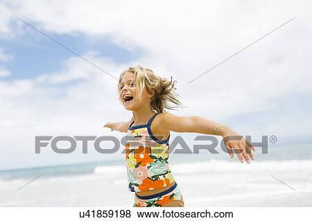 Stock Photo - Girl (6-7) spinning on beach. Fotosearch