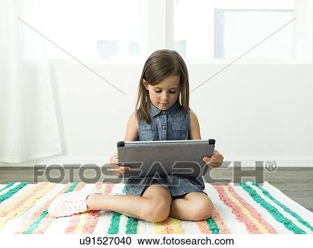Girl (6-7) using digital tablet at home View Large Photo Image Stock Image - Girl (6-7) using digital tablet at home. Fotosearch