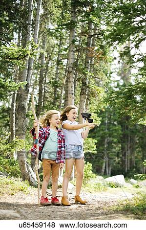 Stock Photo - Girl (8-9) and boy (6-7) standing in forest. Fotosearch