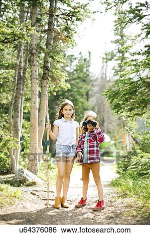Stock Photograph - Girl (8-9) and boy (6-7) standing in forest. Fotosearch