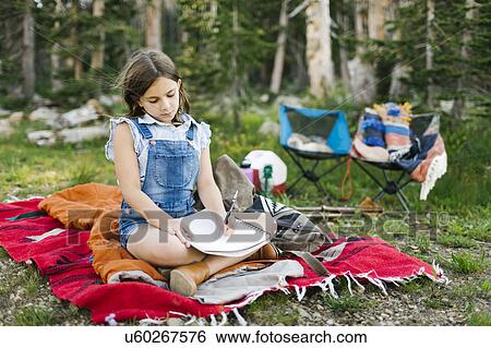 Stock Photograph - Girl (8-9) sitting on blanket in forest. Fotosearch