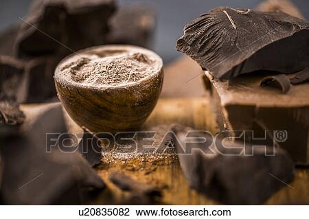 Stock Image - Ground chocolate in wooden bowl next to chunk of chocolate. Fotosearch