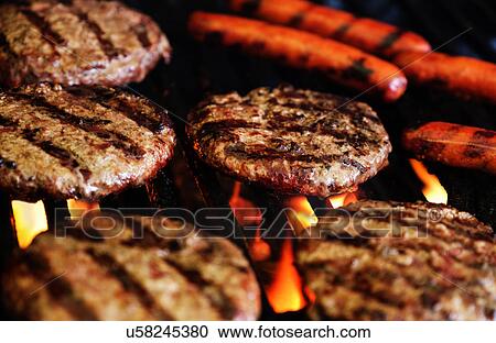 Stock Image - Hamburgers and hot dogs on barbeque grill. Fotosearch