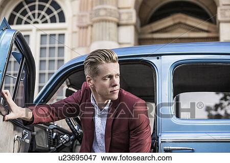 Stock Photo - Handsome man disembarking vintage car. Fotosearch