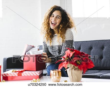 Happy woman on sofa opening Christmas gift View Large Photo Image Stock Image - Happy woman on sofa opening Christmas gift. Fotosearch