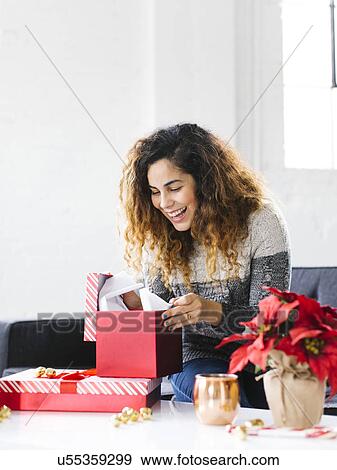 Happy woman on sofa opening Christmas gift View Large Photo Image Stock Photo - Happy woman on sofa opening Christmas gift. Fotosearch
