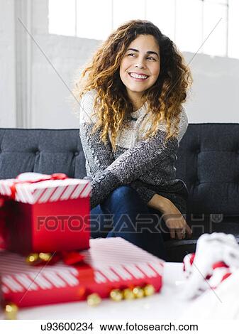Happy woman on sofa with Christmas gifts in foreground View Large Photo Image Picture - Happy woman on sofa with Christmas gifts in foreground. Fotosearch