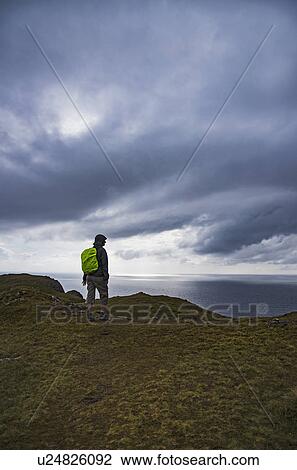 Stock Image - Ireland, County Donegal, Hiker looking at Donegal bay along Wild Atlantic Way. Fotosearch
