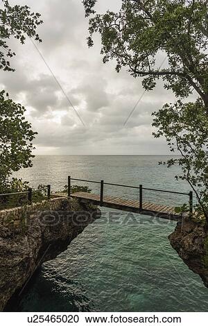 Stock Image - Jamaica, Negril, Footbridge hanging between rocks. Fotosearch