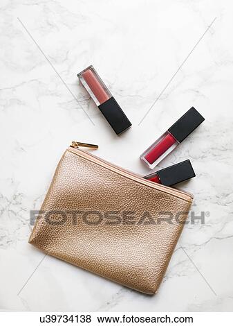 Stock Photo - Lip glosses and purse on marble background. Fotosearch