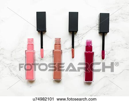 Stock Image - Lip glosses on marble background. Fotosearch