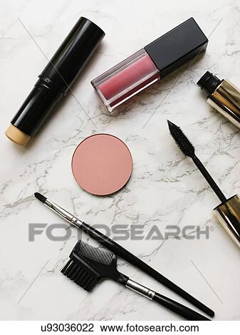 Stock Image - Lip sticks and mascara on marble background. Fotosearch