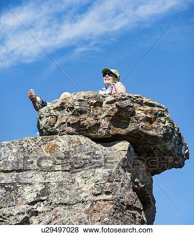 Low angle view of woman sitting on rock View Large Photo Image Stock Photo - Low angle view of woman sitting on rock. Fotosearch