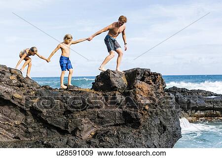 Man and children (6-7, 8-9) walking on rock by sea View Large Photo Image Stock Photo - Man and children (6-7, 8-9) walking on rock by sea. Fotosearch