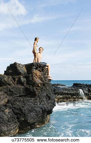 Stock Photography - Man and girl (6-7) resting on cliff. Fotosearch