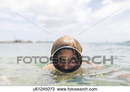 Stock Image - Man wearing swimming goggles swimming in sea. Fotosearch