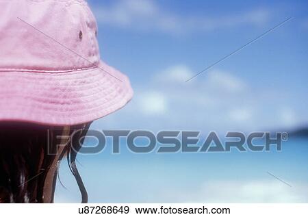 Stock Photo - Mature woman in pink sun hat on Caribbean beach. Fotosearch