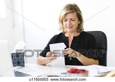 Stock Image - Mature woman opening letter. Fotosearch