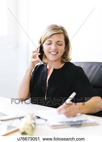 Mature woman talking on mobile phone and taking notes View Large Photo Image Stock Image - Mature woman talking on mobile phone and taking notes. Fotosearch