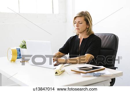 Picture - Mature woman working on laptop. Fotosearch