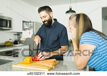 Stock Image - Mid adult couple cooking together. Fotosearch