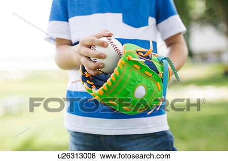 Mid section of boy (6-7) holding baseball ball View Large Photo Image Stock Photo - Mid section of boy (6-7) holding baseball ball. Fotosearch