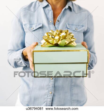 Stock Image - Mid section of Mature woman holding gift. Fotosearch