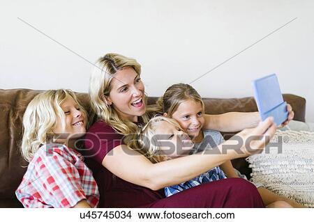 Picture - Mother and children (4-5, 6-7, 8-9) taking selfie with digital tablet. Fotosearch