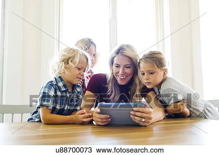 Stock Image - Mother and children (4-5, 6-7, 8-9) with digital tablet. Fotosearch