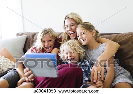 Stock Image - Mother and children (4-5, 6-7, 8-9) taking selfie with digital tablet. Fotosearch