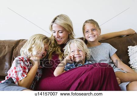 Stock Photo - Mother and children (4-5, 6-7, 8-9) resting in living room. Fotosearch