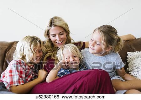 Stock Photography - Mother and children (4-5, 6-7, 8-9) resting in living room. Fotosearch