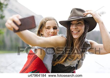 Picture - Mother and daughter (8-9) taking selfie. Fotosearch