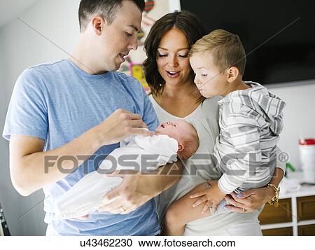 Stock Image - Mother and father carrying son (4-5) and daughter (0-1 months). Fotosearch